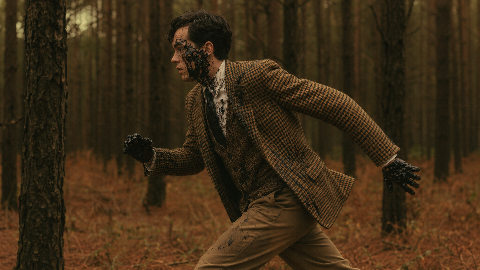 The young man runs through the pine forest as a black substance spreads across his face and hands.